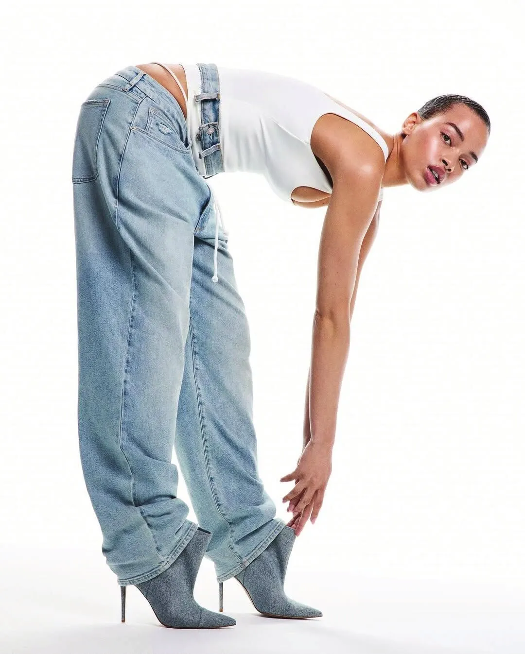 Model bent double in light-wash wide-leg jeans and a white top