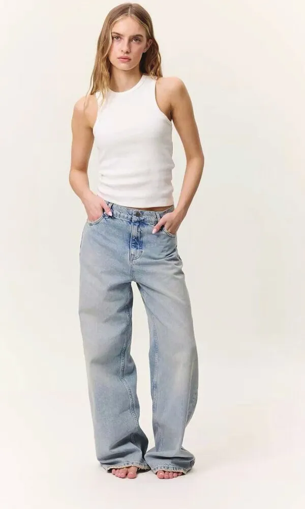 Model standing in light-wash straight jeans and a white tank